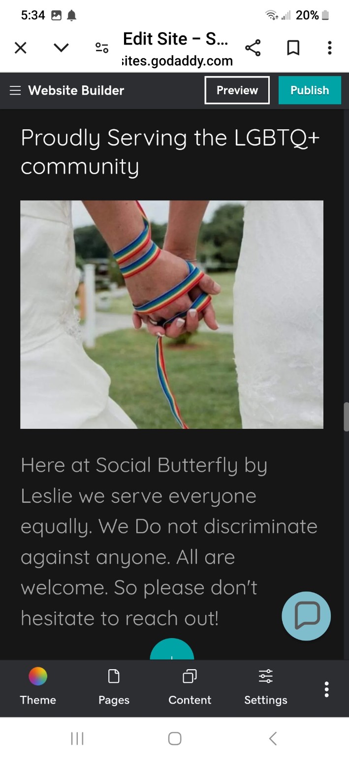 Two brides holding hands joined by a rainbow handfasting ribbon